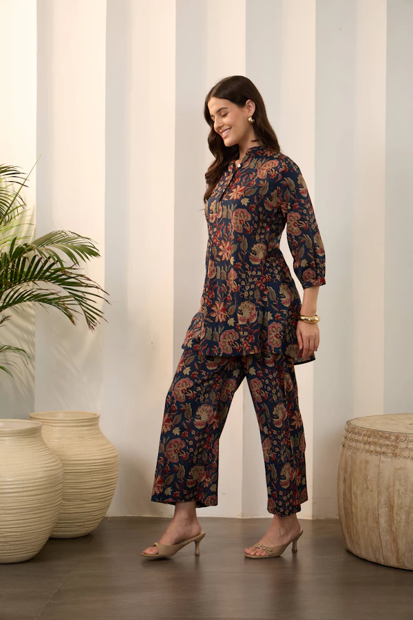 A woman in a navy shirt and cropped trousers covered in small rust and white flowers.