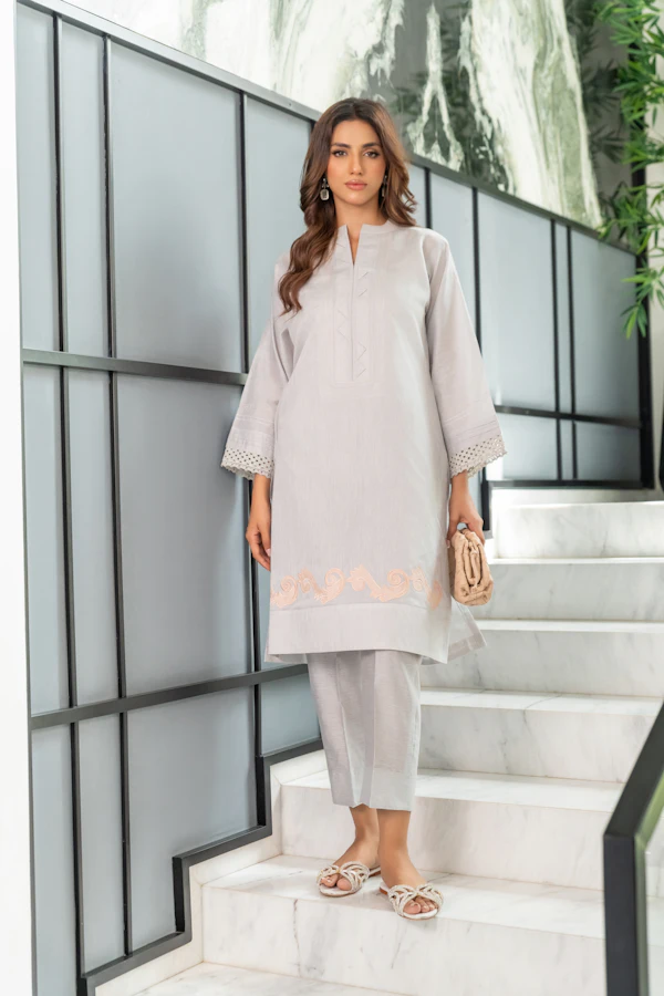 A woman in a pearl grey cotton silk kurta and trousers standing on white stairs.